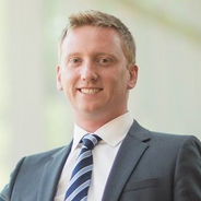 Dominic Packer in a gray suit